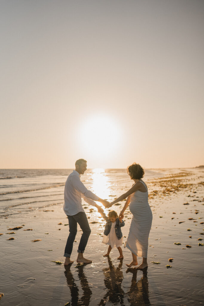 Famille jouant sur la plage au coucher du soleil lors d'une séance photo