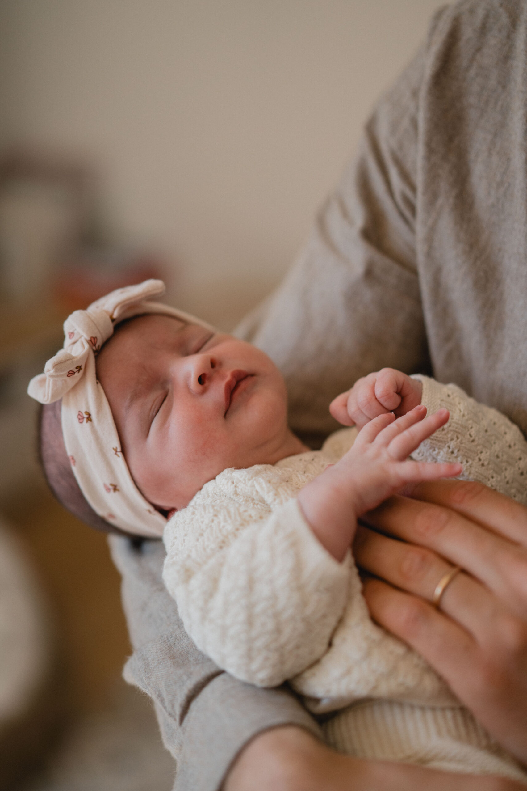 Gros plan sur un nouveau-né paisiblement installé dans les bras de son parent.
