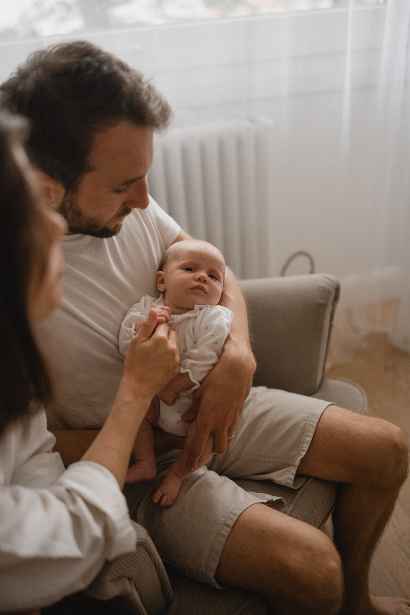 Jeunes parents admirant leur nouveau-né pendant une séance photo à domicile.