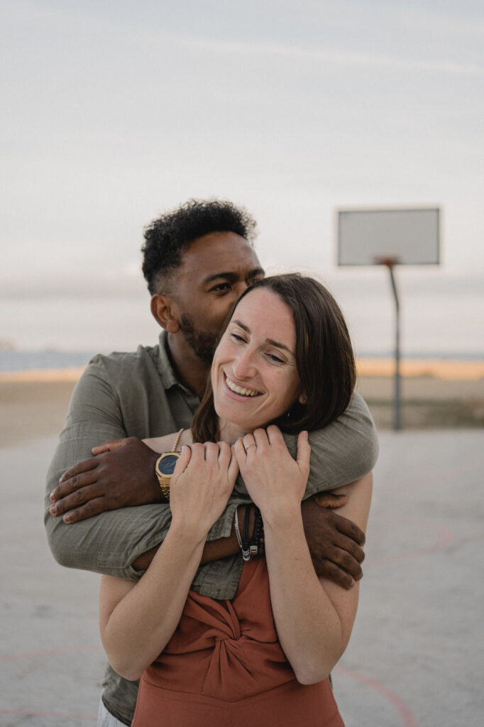 Couple enlacé sur un terrain de basket en bord de mer