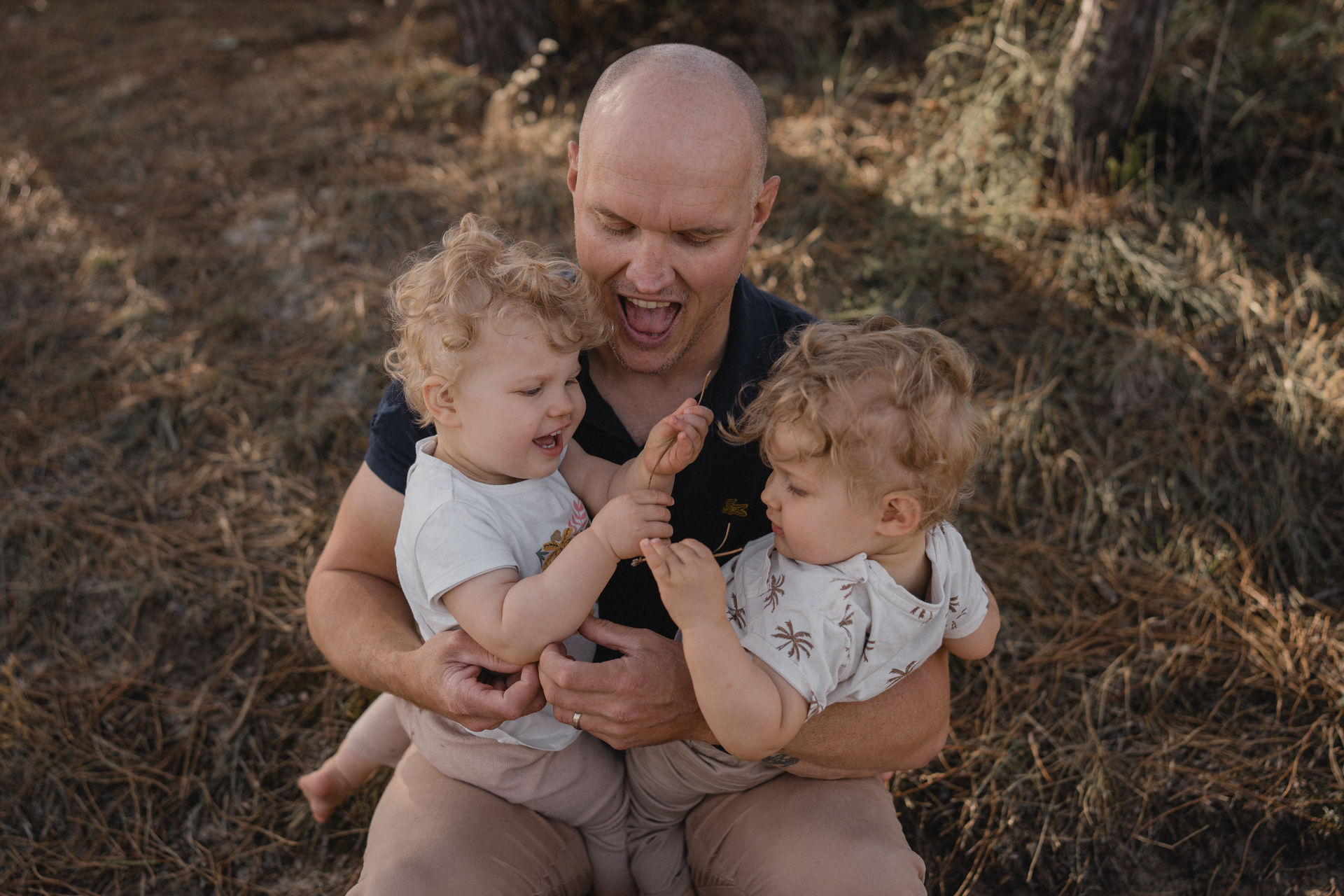 Papa jouant avec ses deux jeunes enfants lors d'une séance photo de famille en extérieur