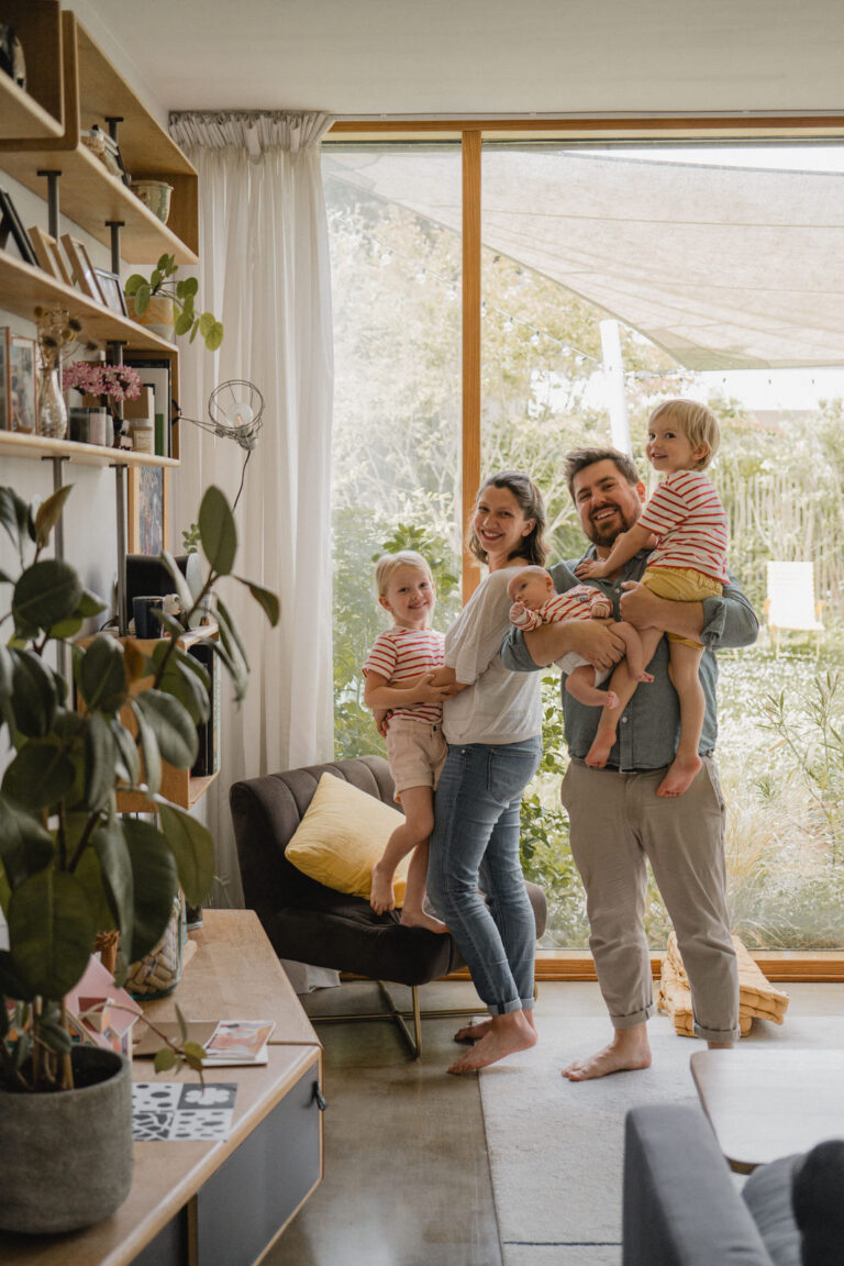 Famille réunie avec son nouveau-né dans son salon lors d'une séance photo à domicile.