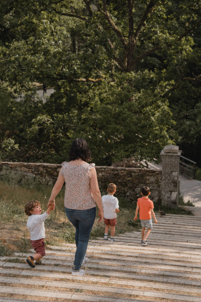 Maman marchant avec ses enfants pendant une séance photo famille naturelle en extérieur