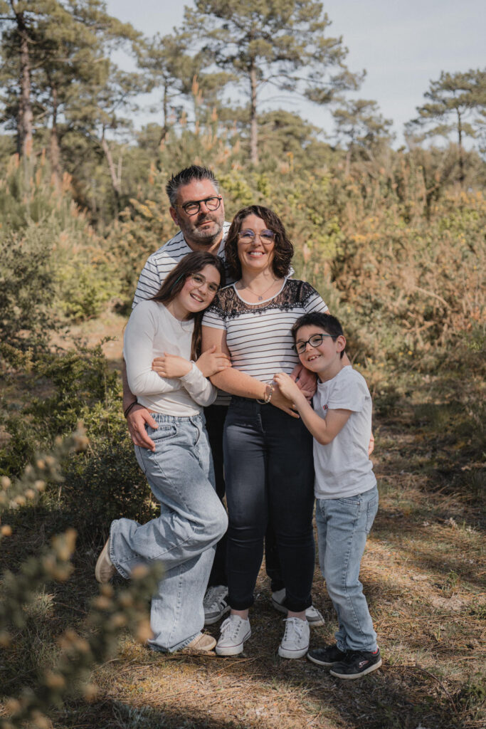 Portrait naturel d'une famille de quatre personnes réalisé dans une forêt de pins, en bord de mer.