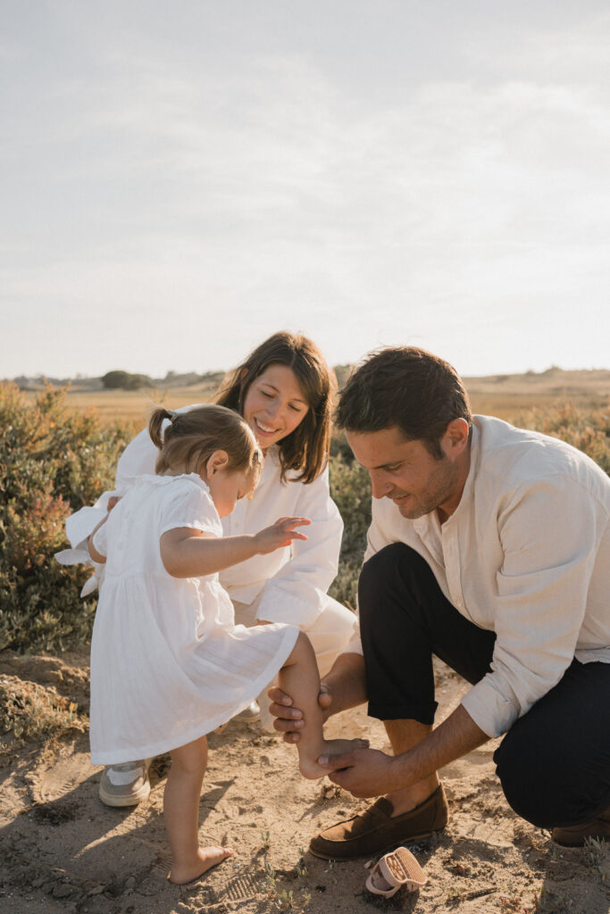 Parents en train de mettre les chaussures de leur petite fille lors d'une promenade en famille