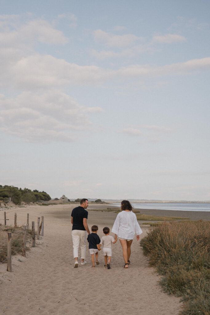 Famille marchant sur la plage pendant une séance photo famille au bord de l'océan