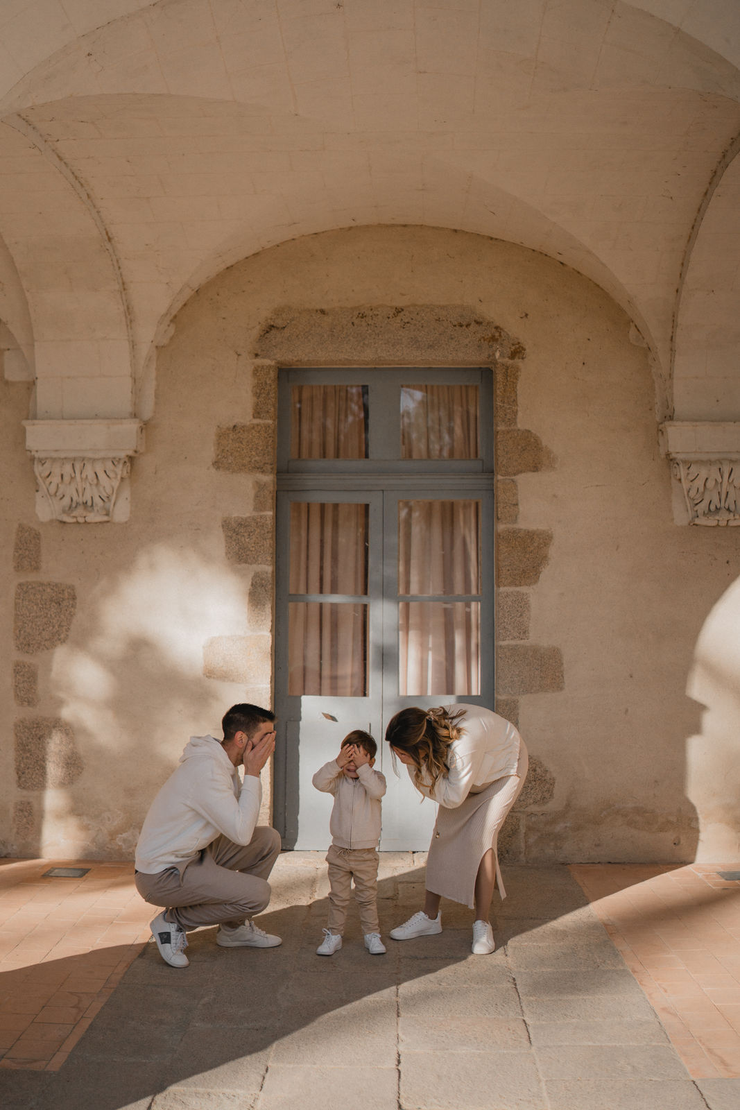 Parents jouant avec leur enfant sous les arches d'un bâtiment ancien