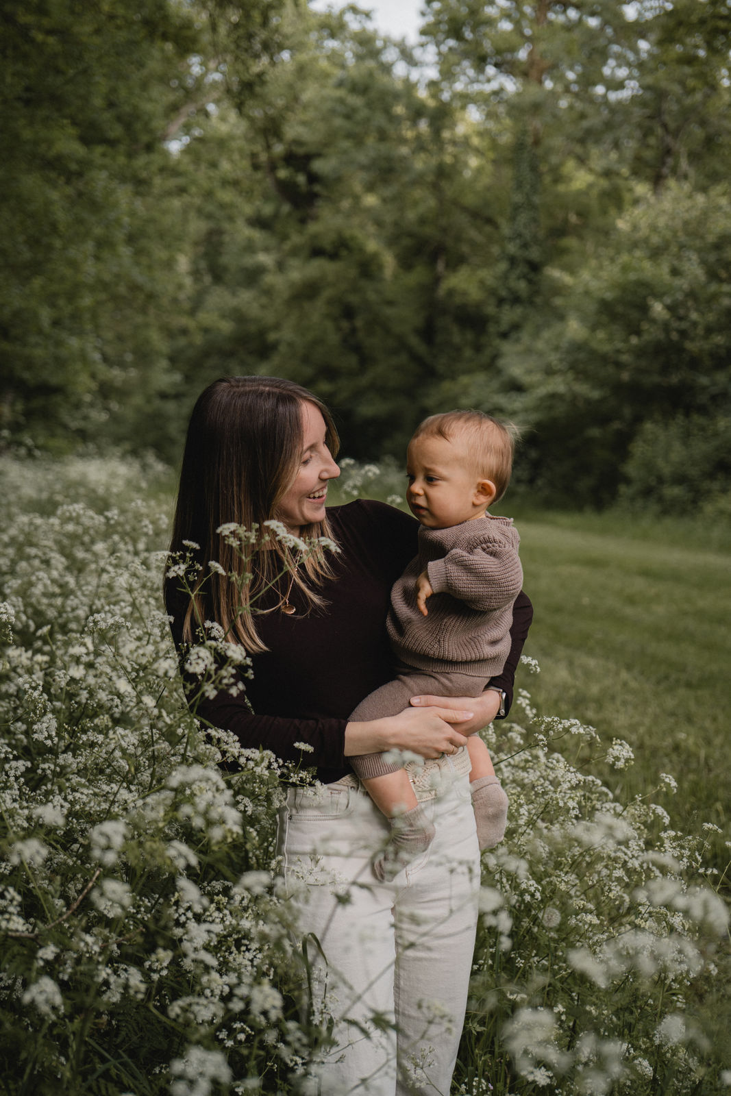 Maman portant son enfant dans une prairie fleurie