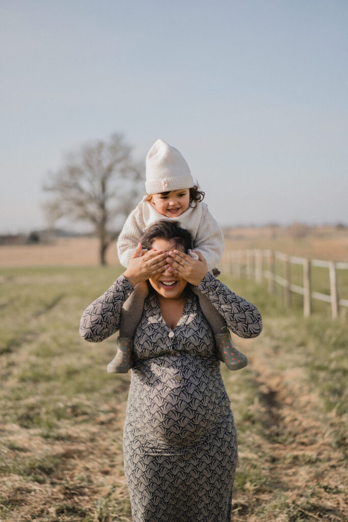 Jeune maman portant son enfant sur les épaules pendant sa deuxième grossesse