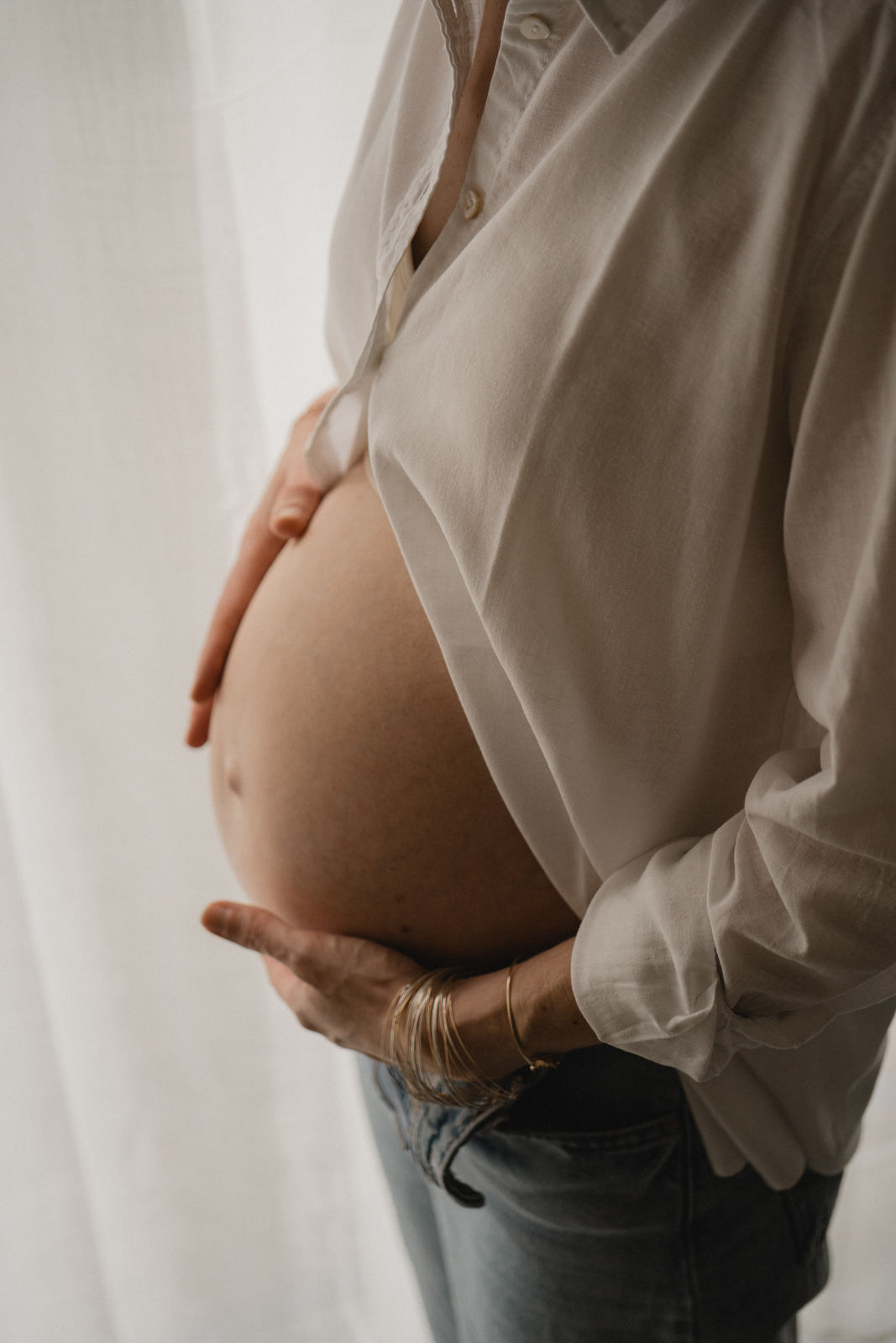 Gros plan sur le ventre d'une femme enceinte caressé avec douceur pendant une séance photo.