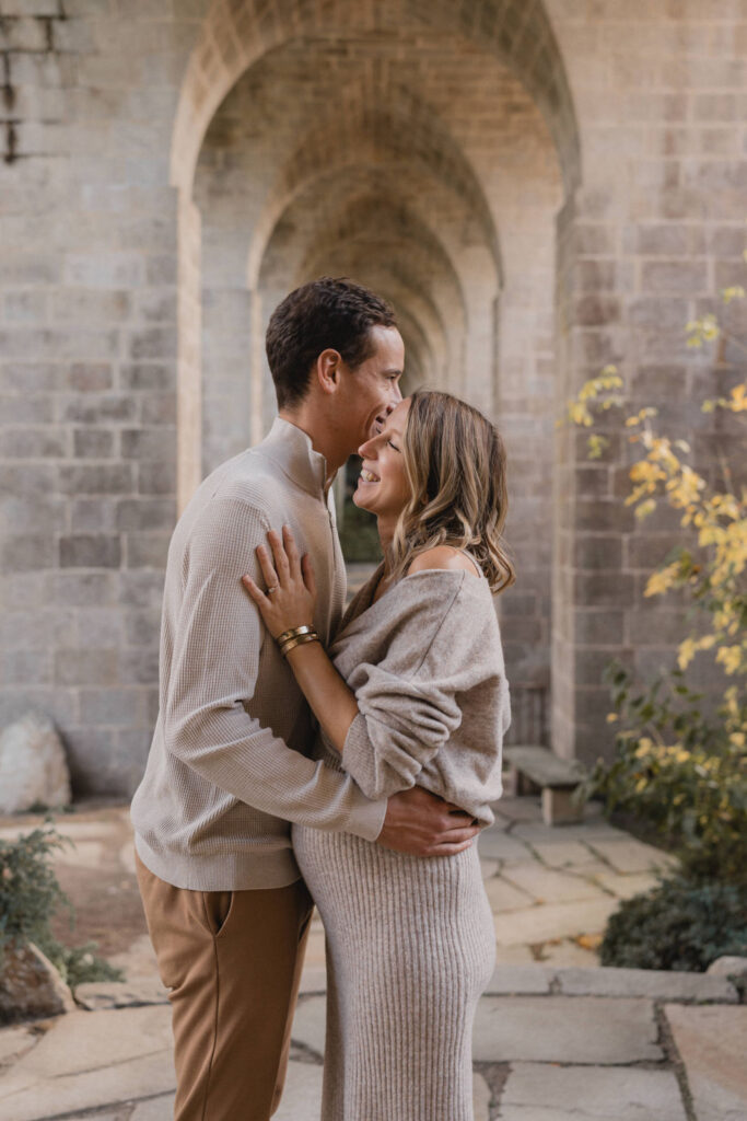 Jeunes parents partageant un moment de tendresse sous une arche en pierre