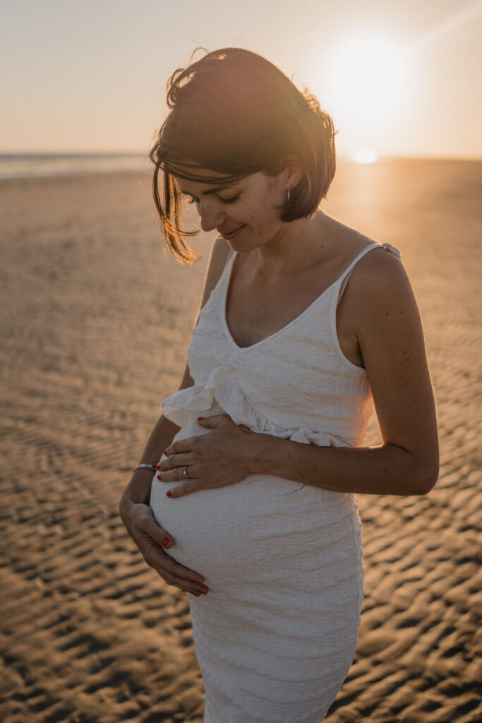 Lumière dorée sur une future maman en bord de mer