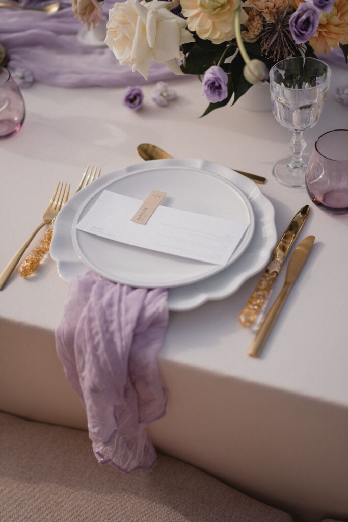 Détail d'une table de réception décorée de vaisselle et de fleurs.