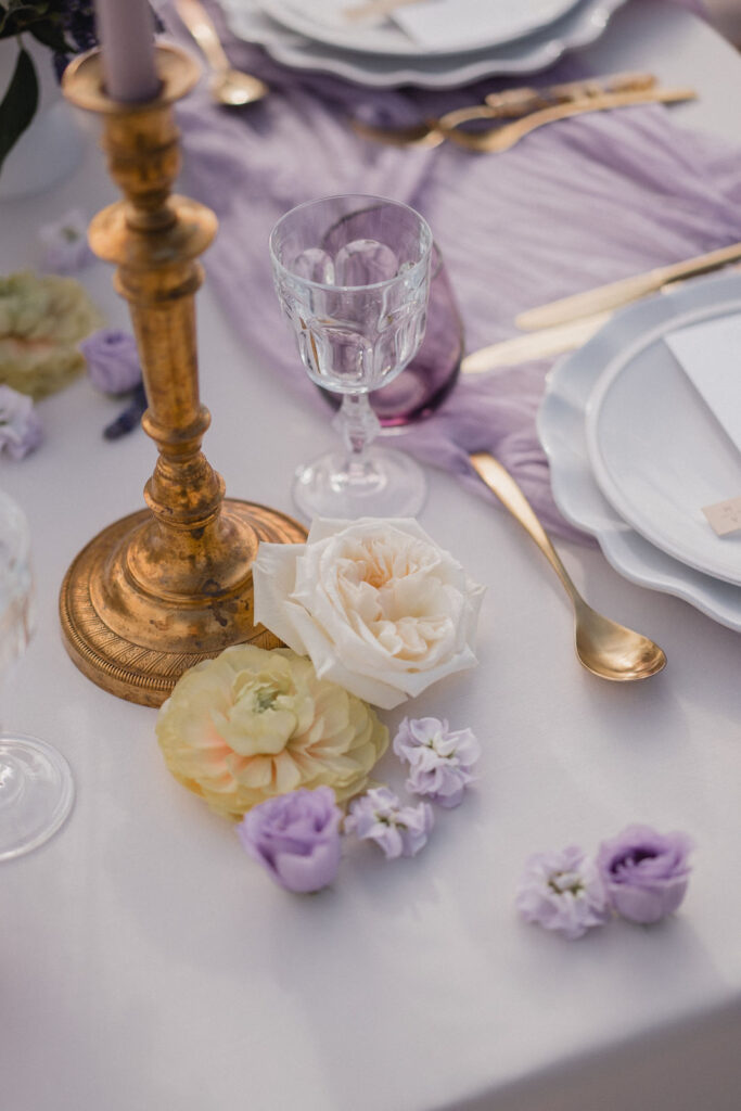 Détail de la décoration de table avec bougies, fleurs et vaisselle.