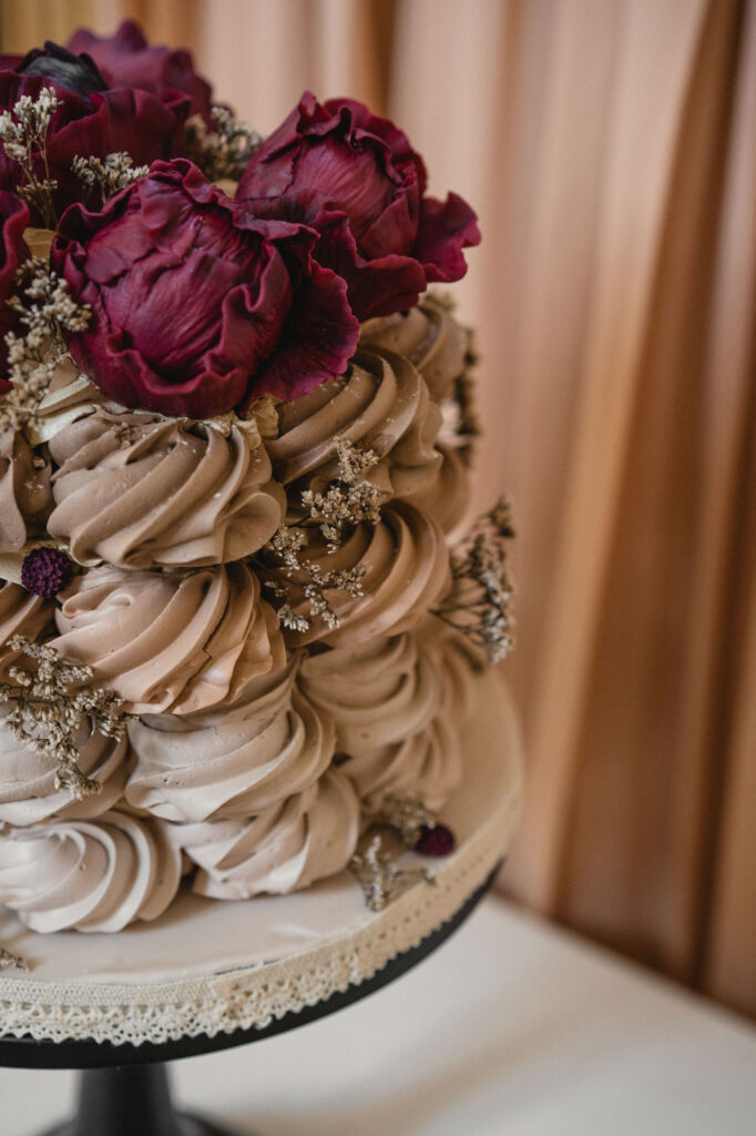 Gâteau de mariage décoré de fleurs aux teintes bordeaux.