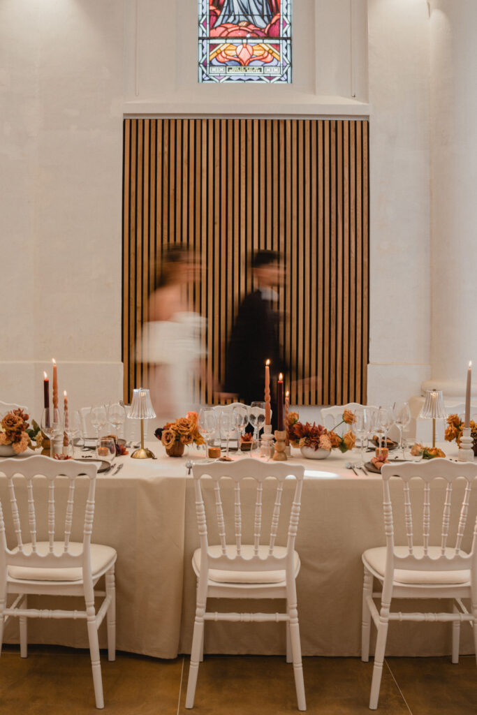 Les mariés passent devant leur table de réception dans un léger flou de mouvement.