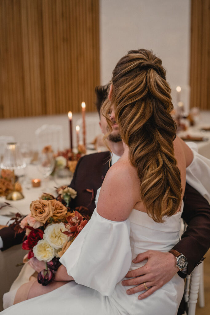 La mariée enlace son époux pendant le dîner de mariage.