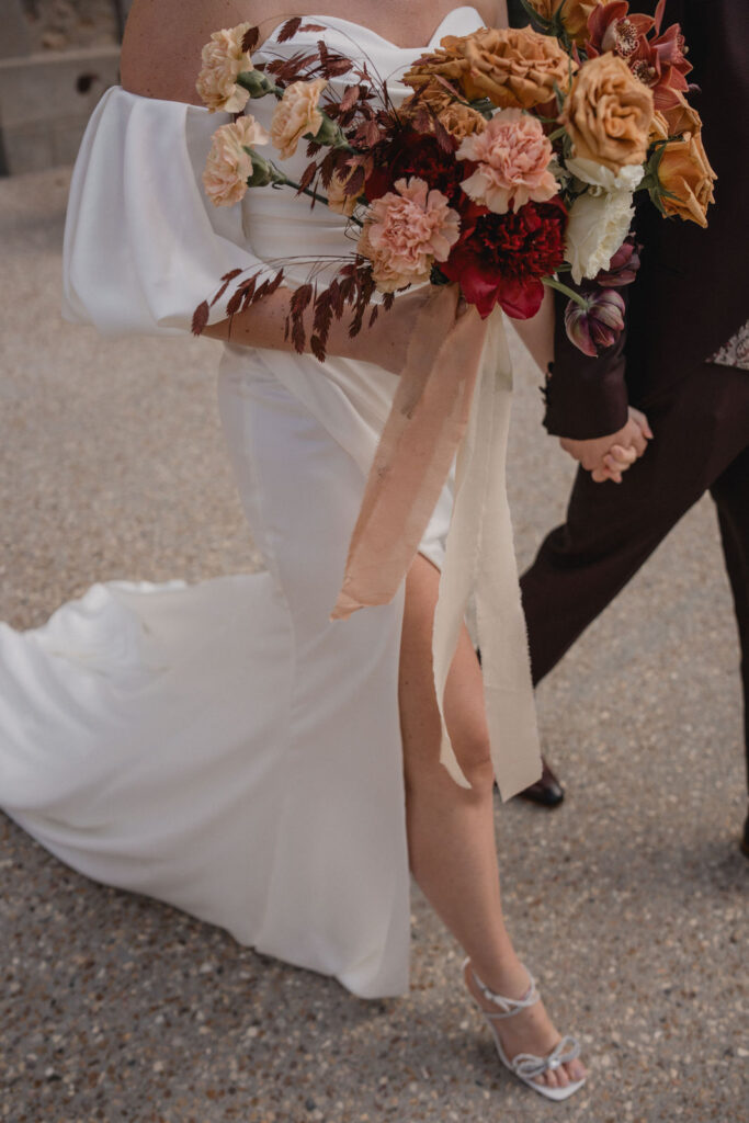 La mariée tient son bouquet en marchant aux côtés de son époux.
