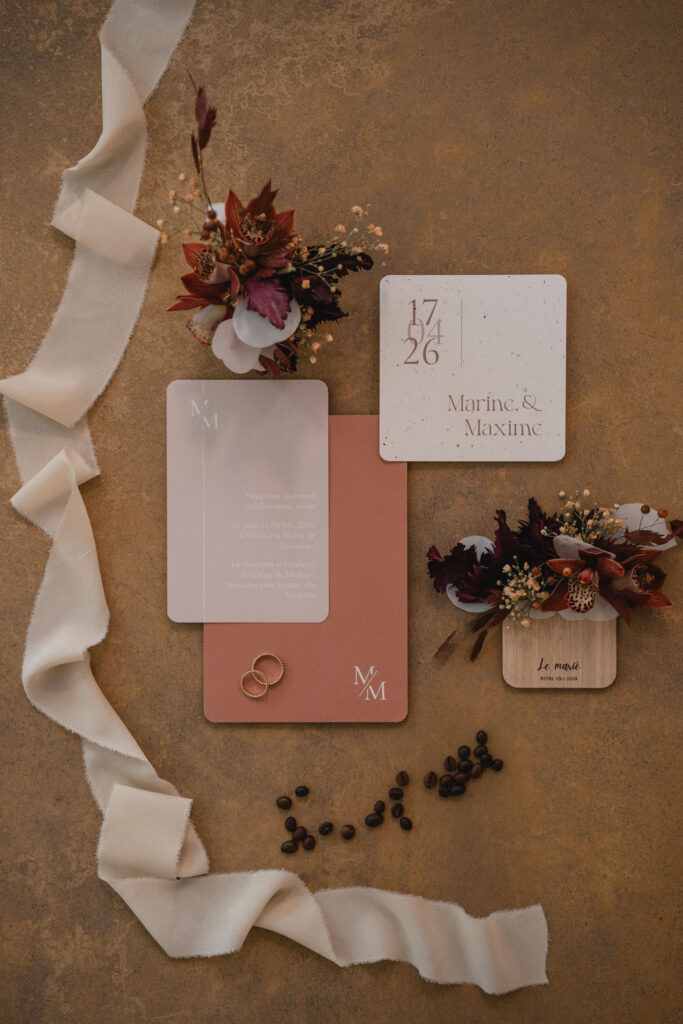 Papeterie de mariage, alliances et compositions florales soigneusement disposées.