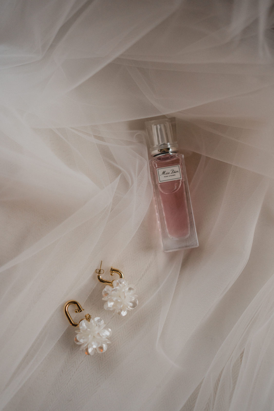 Parfum et bijoux de la mariée posés sur son voile