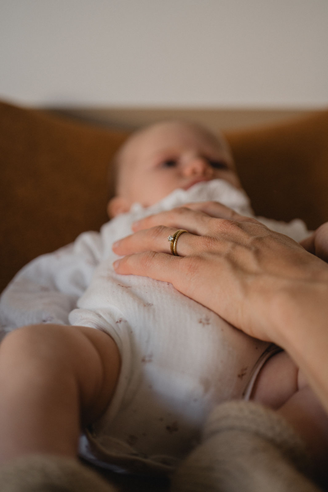 Parent posant délicatement sa main sur son nouveau-né pendant une séance photo à domicile.