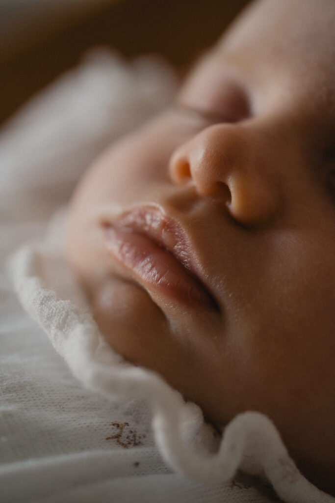 Gros plan sur le visage endormi d'un nouveau-né pendant une séance photo naissance.