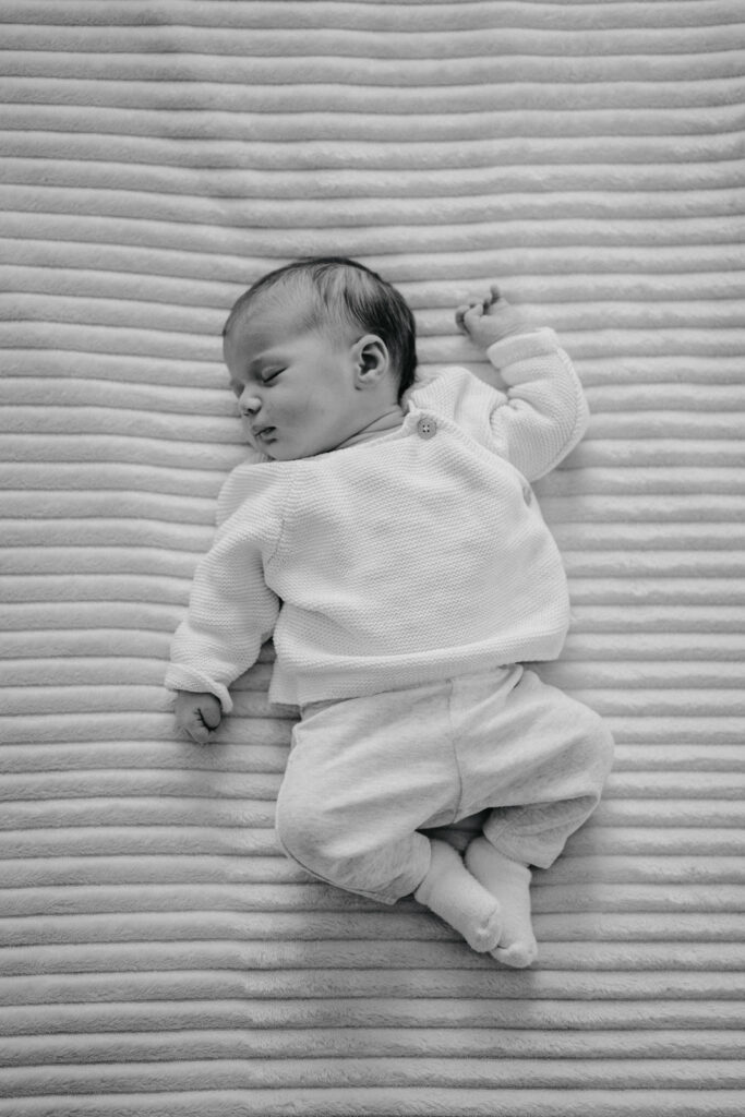 Nouveau-né endormi photographié en noir et blanc lors d'une séance photo naissance.