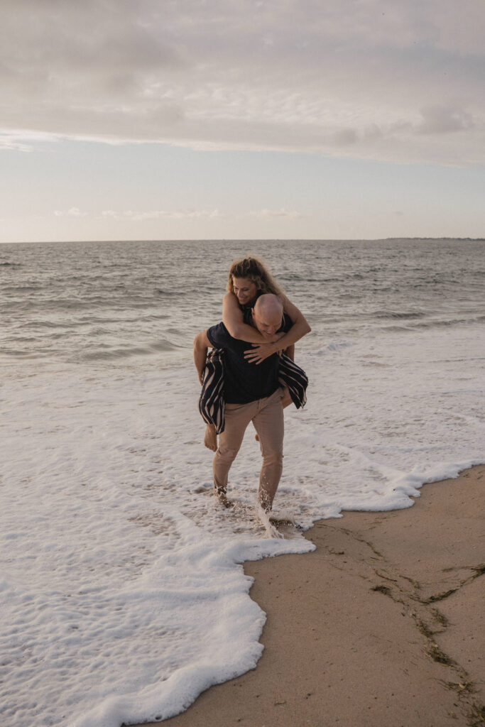 Couple marchant dans les vagues au bord de la mer