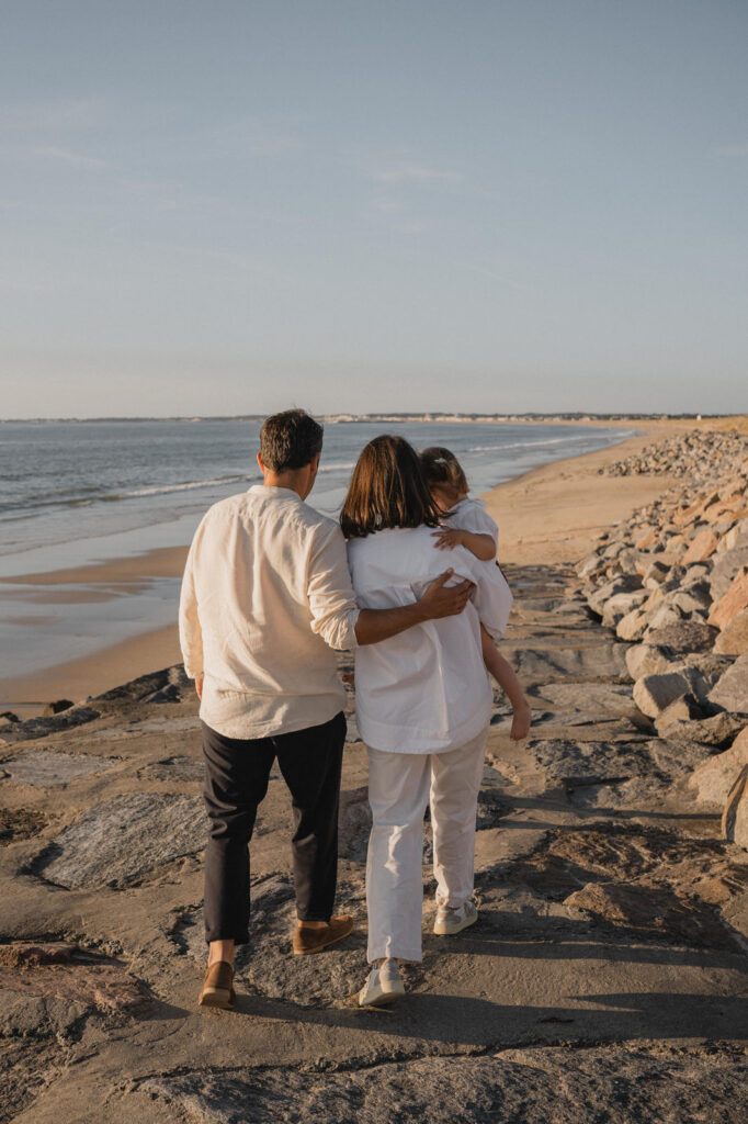 Parents marchant enlacés avec leur enfant sur une plage