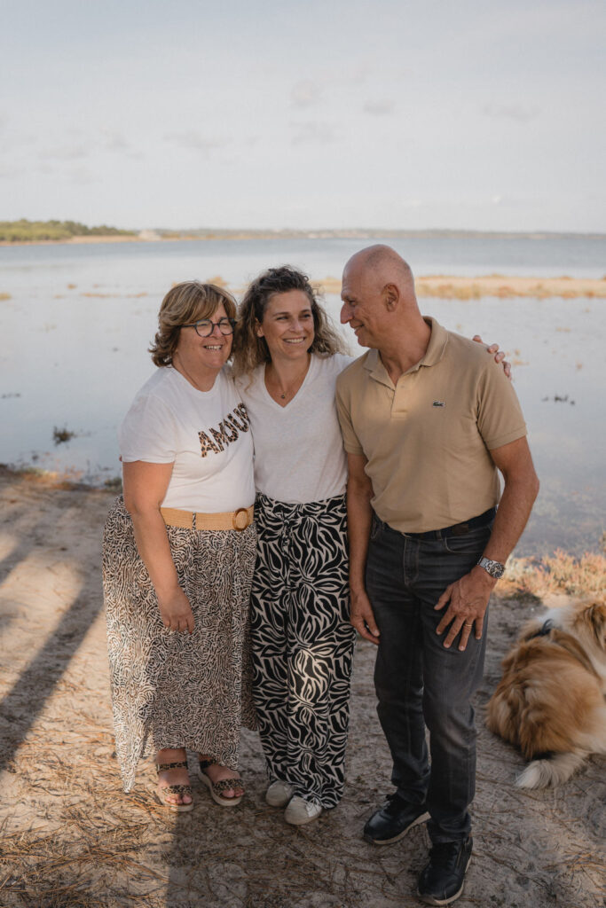 Une fille unique et ses parents souriant au bord de l'eau pendant une séance photo en famille