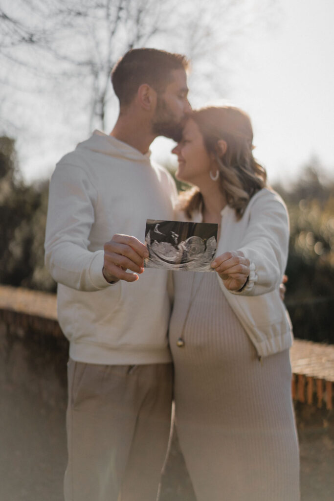 Futurs parents présentant la première échographie de leur bébé lors d'une séance photo grossesse.